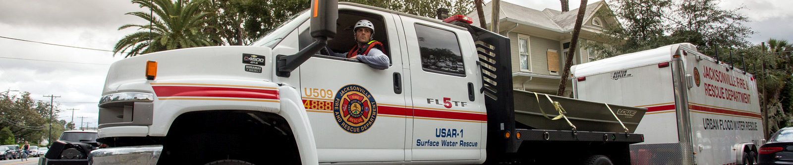 A man driving a fire and rescue truck pulling a trailer